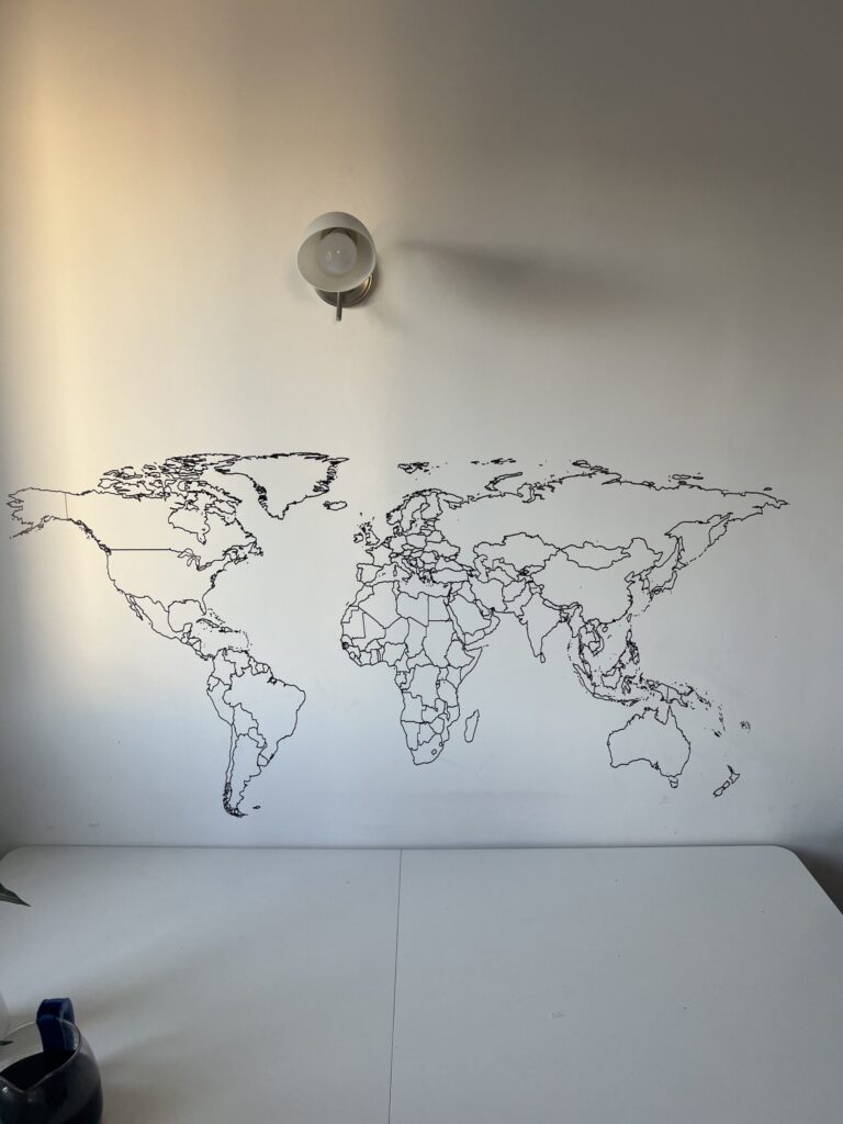 Minimalistyczna mapa świata z cienkich linii na białej ścianie