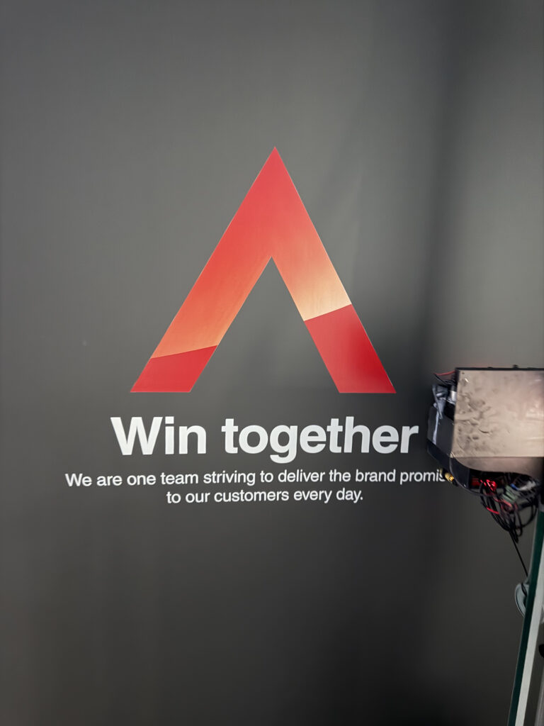 Hasło firmowe Win together wydrukowane na ścianie biura