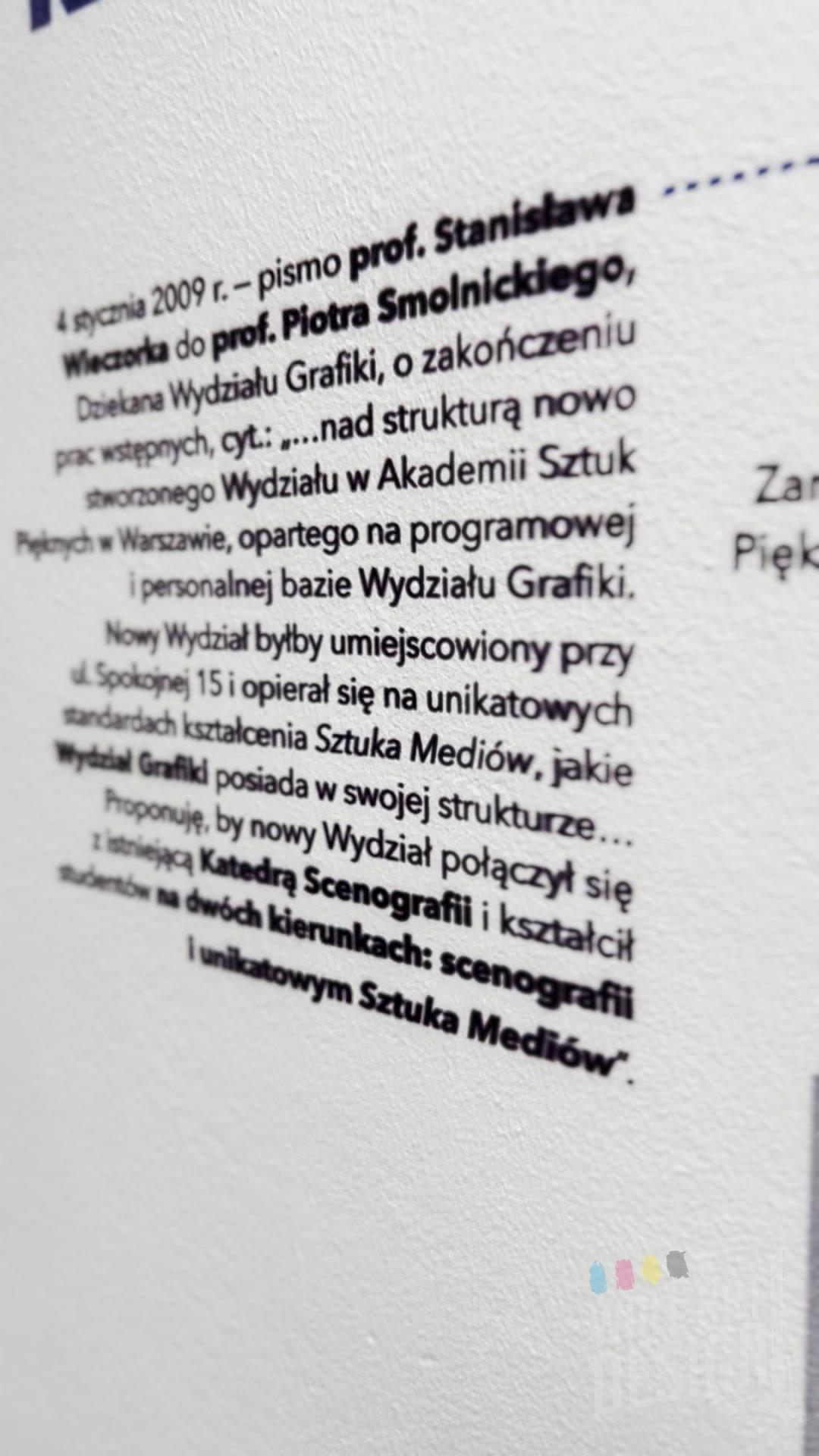 Zbliżenie ostrego, drobnego tekstu wydrukowanego UV na ścianie galerii ASP w Warszawie