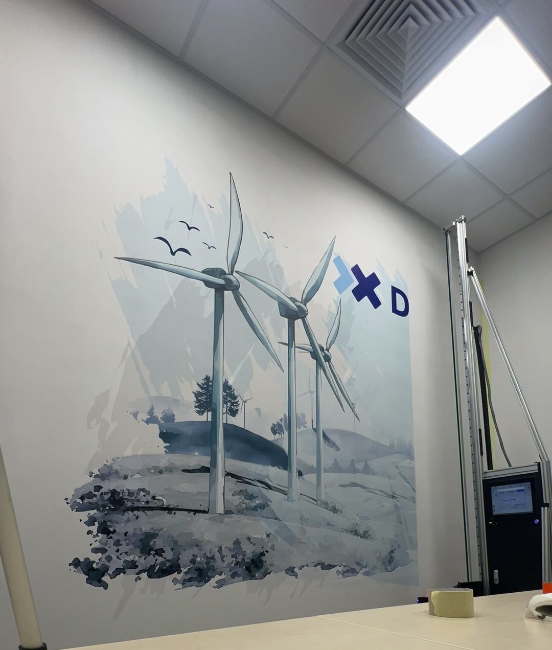 Drukarka ścienna UV drukuje wiatraki i logo DWT na ścianie sali konferencyjnej