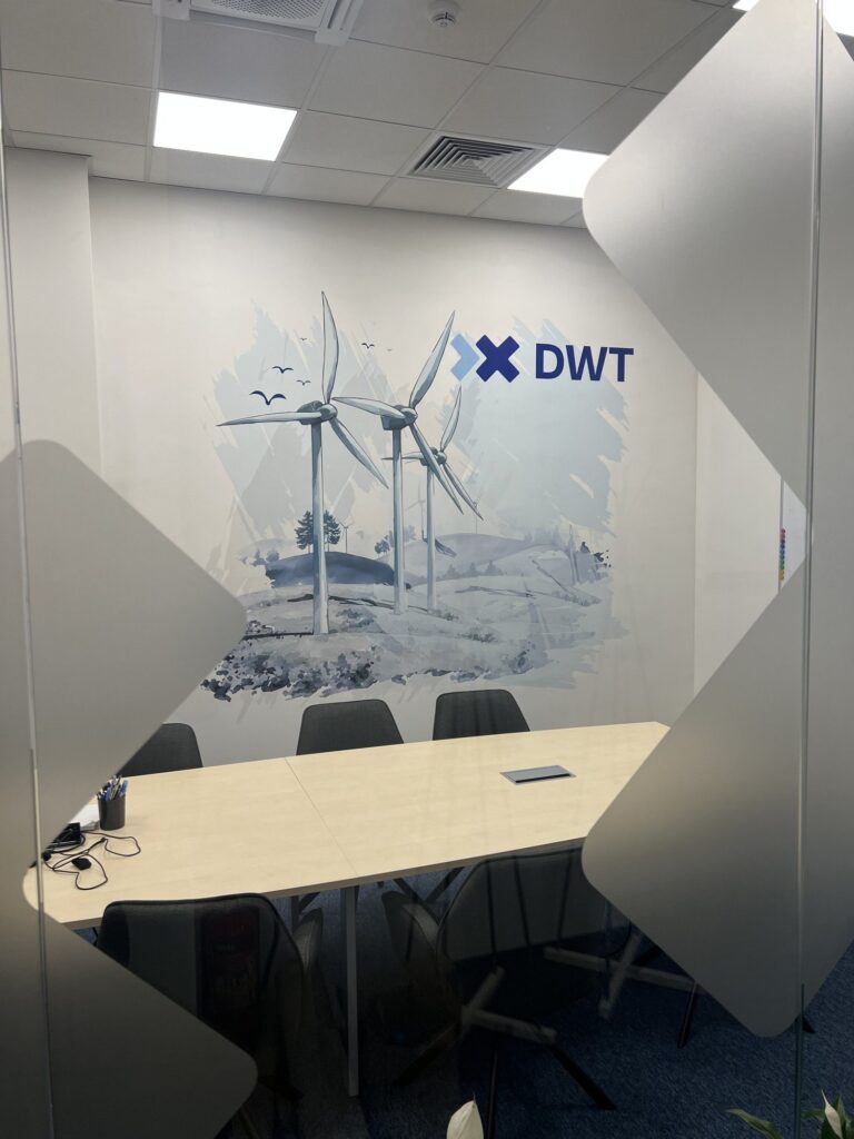 Sala konferencyjna DWT w Poznaniu – akwarelowy krajobraz z wiatrakami i logo DWT wydrukowany UV na ścianie