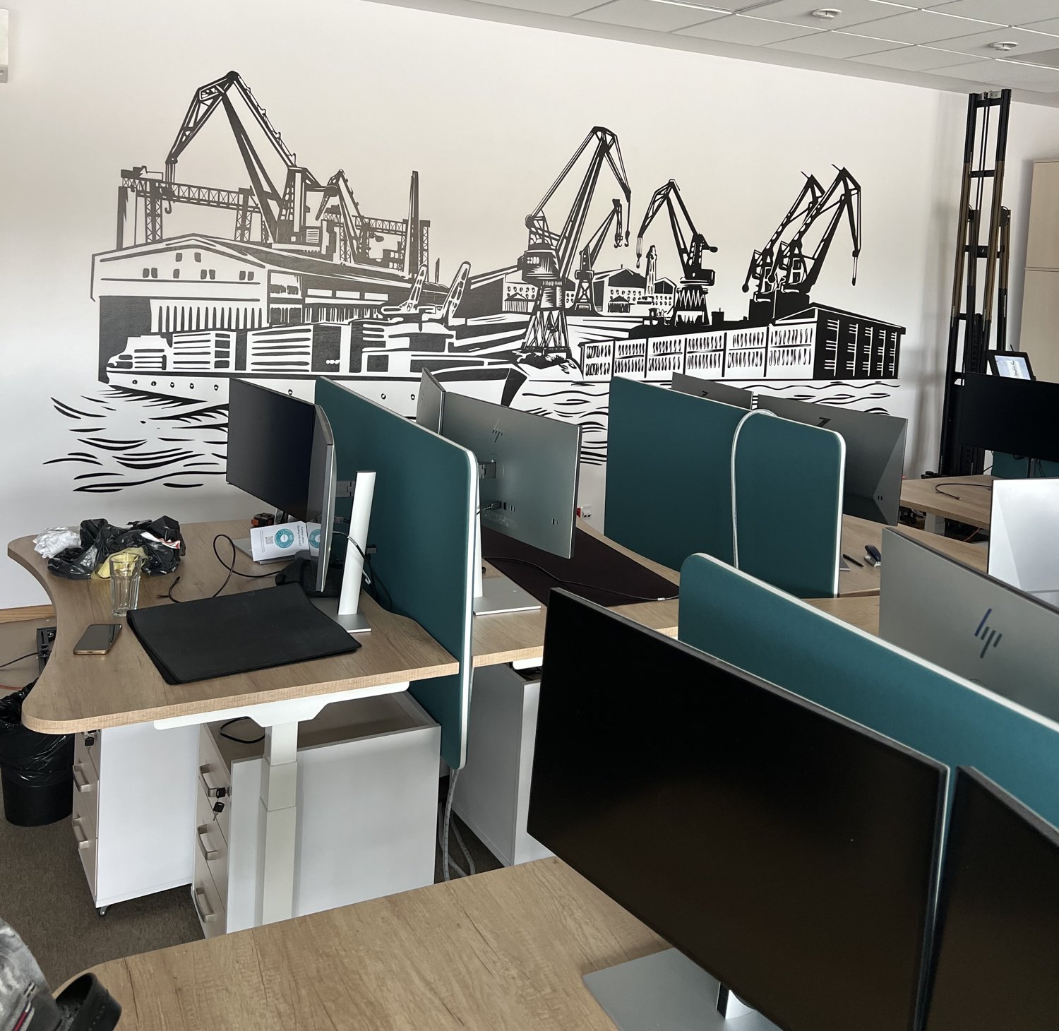 Grafika portu wydrukowana na ścianie biura Kongsberg nad stanowiskami pracy