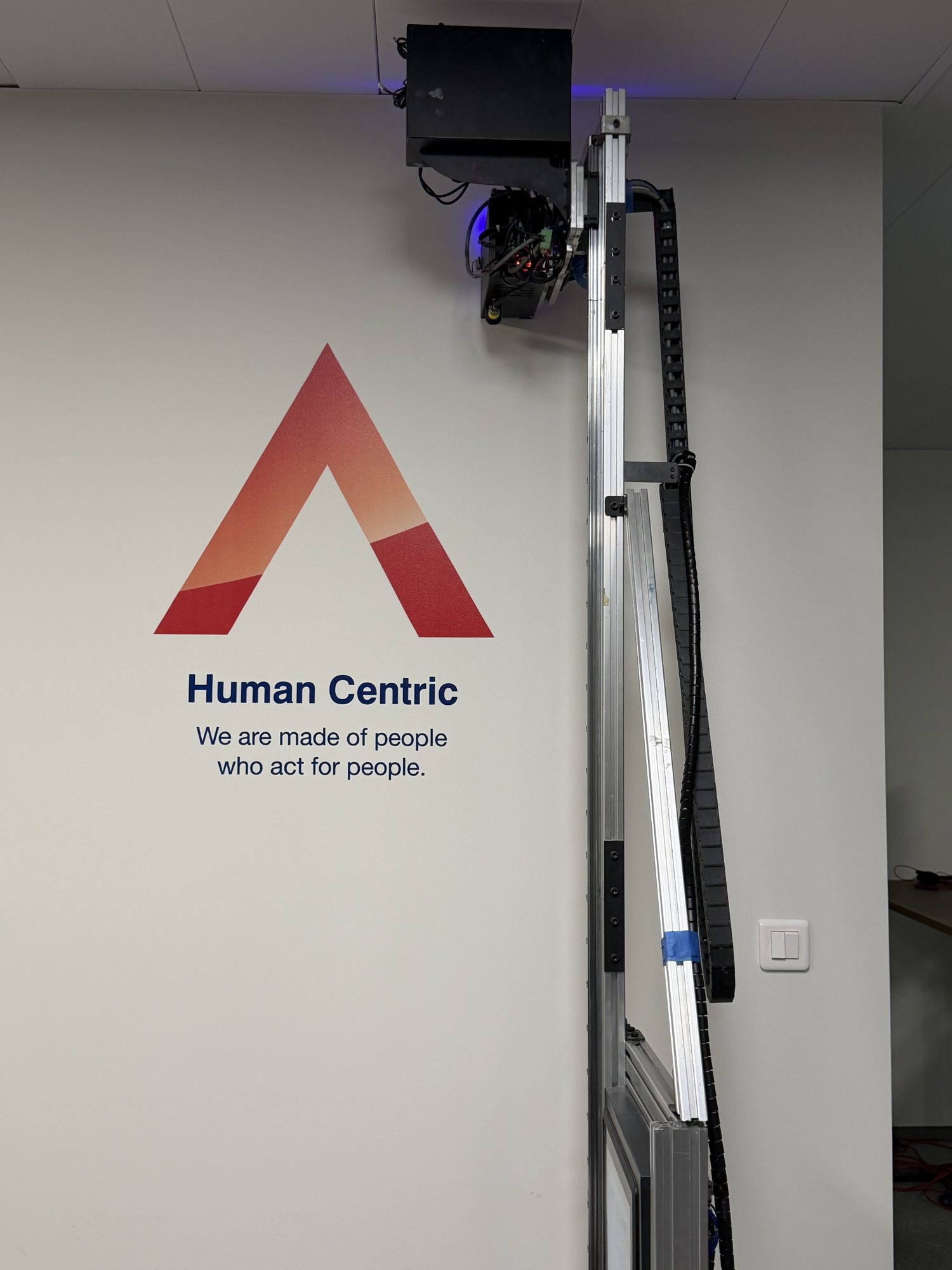 Sygnet Leasys z hasłem Human Centric wydrukowany UV na białej ścianie biura
