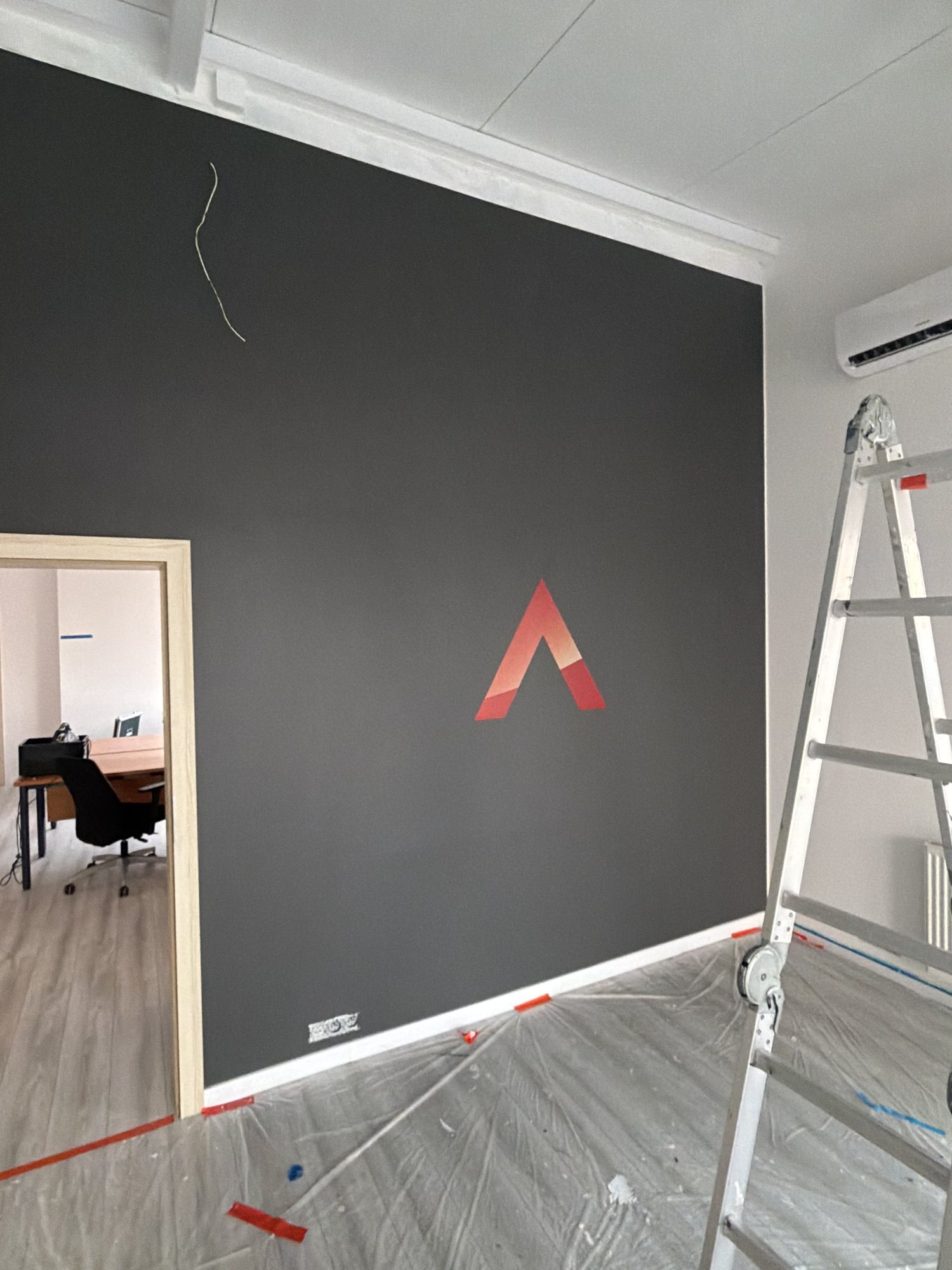 Mały sygnet Leasys wydrukowany na grafitowej ścianie w sali biura