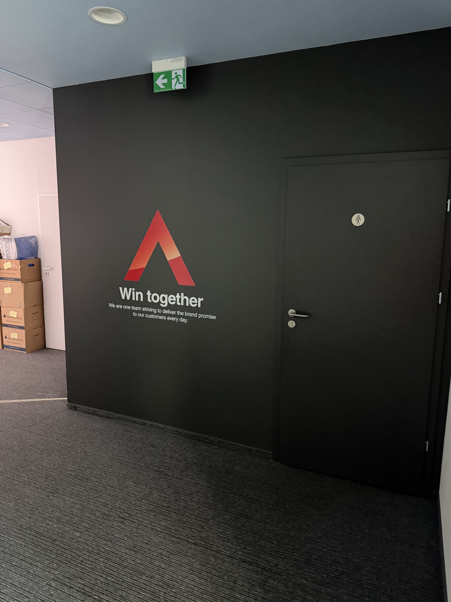 Biuro Leasys w Warszawie – grafitowa ściana z sygnetem Leasys i hasłem Win together wydrukowanymi UV