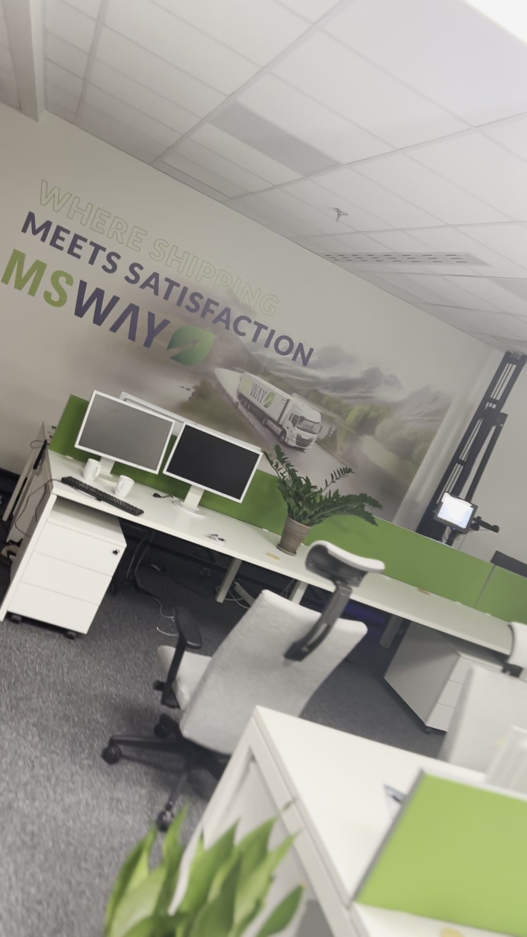 Gotowa ściana w biurze MS WAY – logo, hasło Where shipping meets satisfaction i ciężarówka w krajobrazie