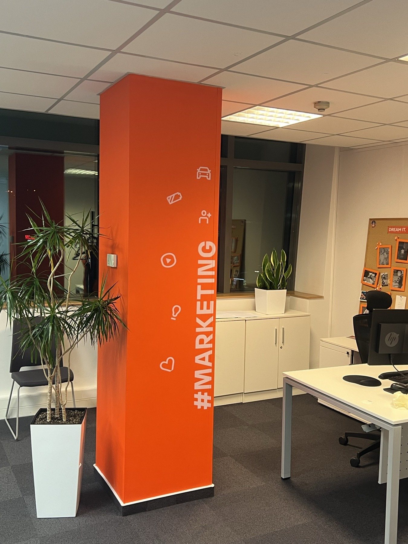 Pomarańczowa kolumna z napisem #MARKETING i ikonami w open space biura RCI Bank