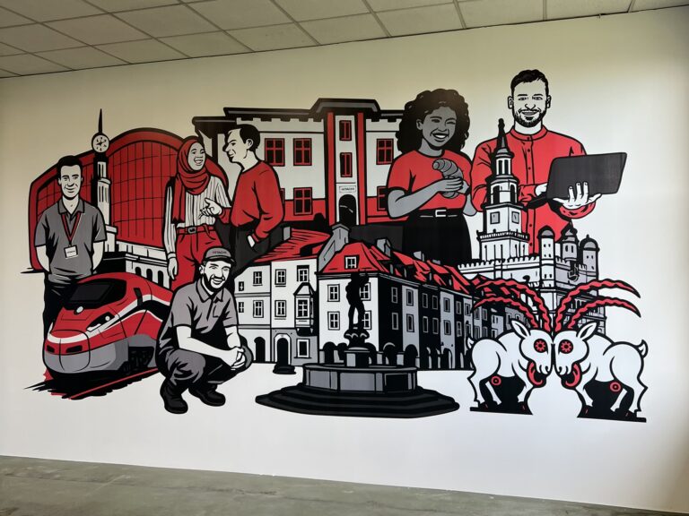 Mural dla Hitachi w Poznaniu – druk ścienny UV 3 × 7 m z motywami Poznania: koziołki, ratusz, kamienice i pociąg