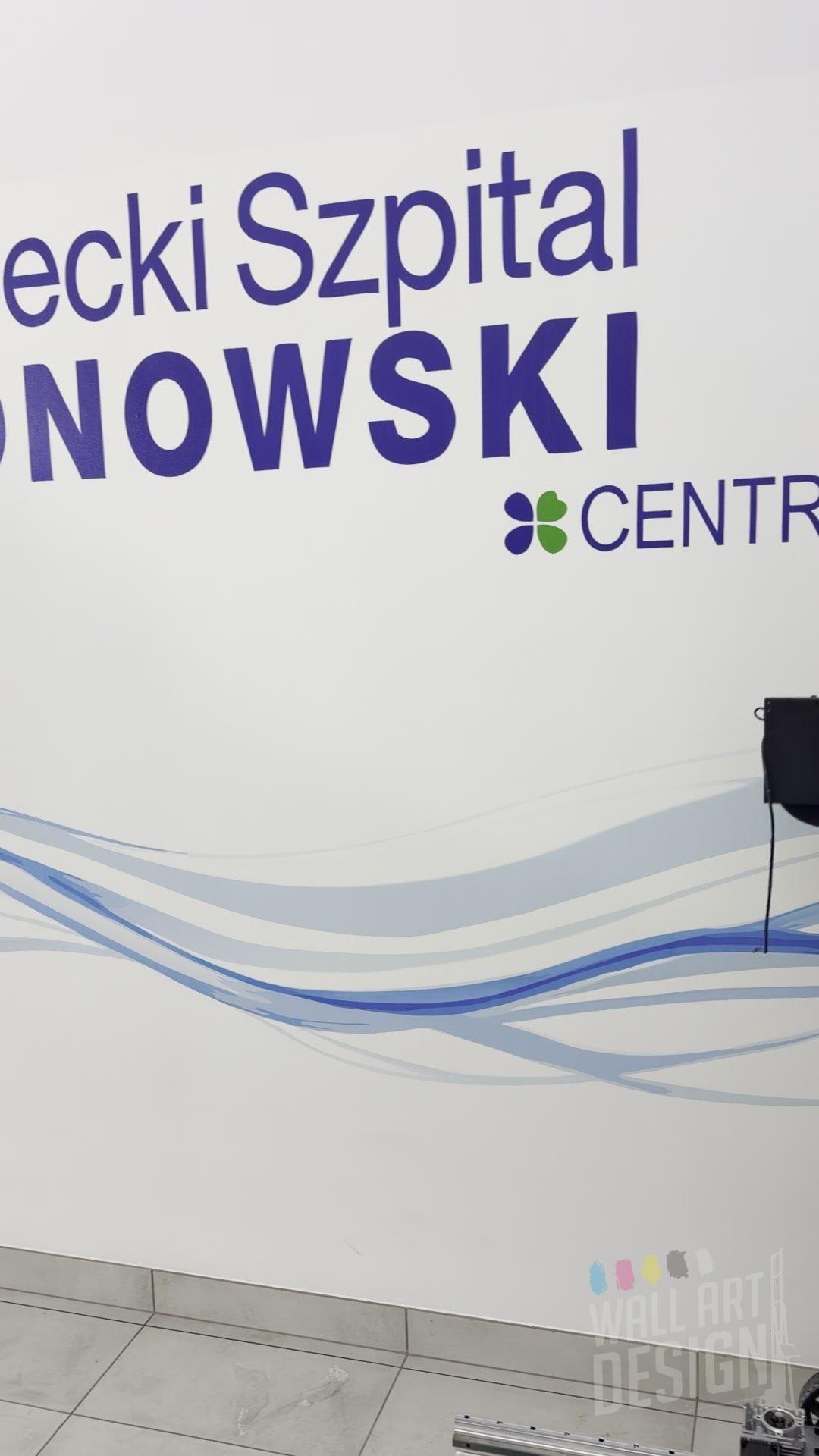 Zbliżenie fal i napisu Mazowiecki Szpital Bródnowski wydrukowanych UV na ścianie basenu