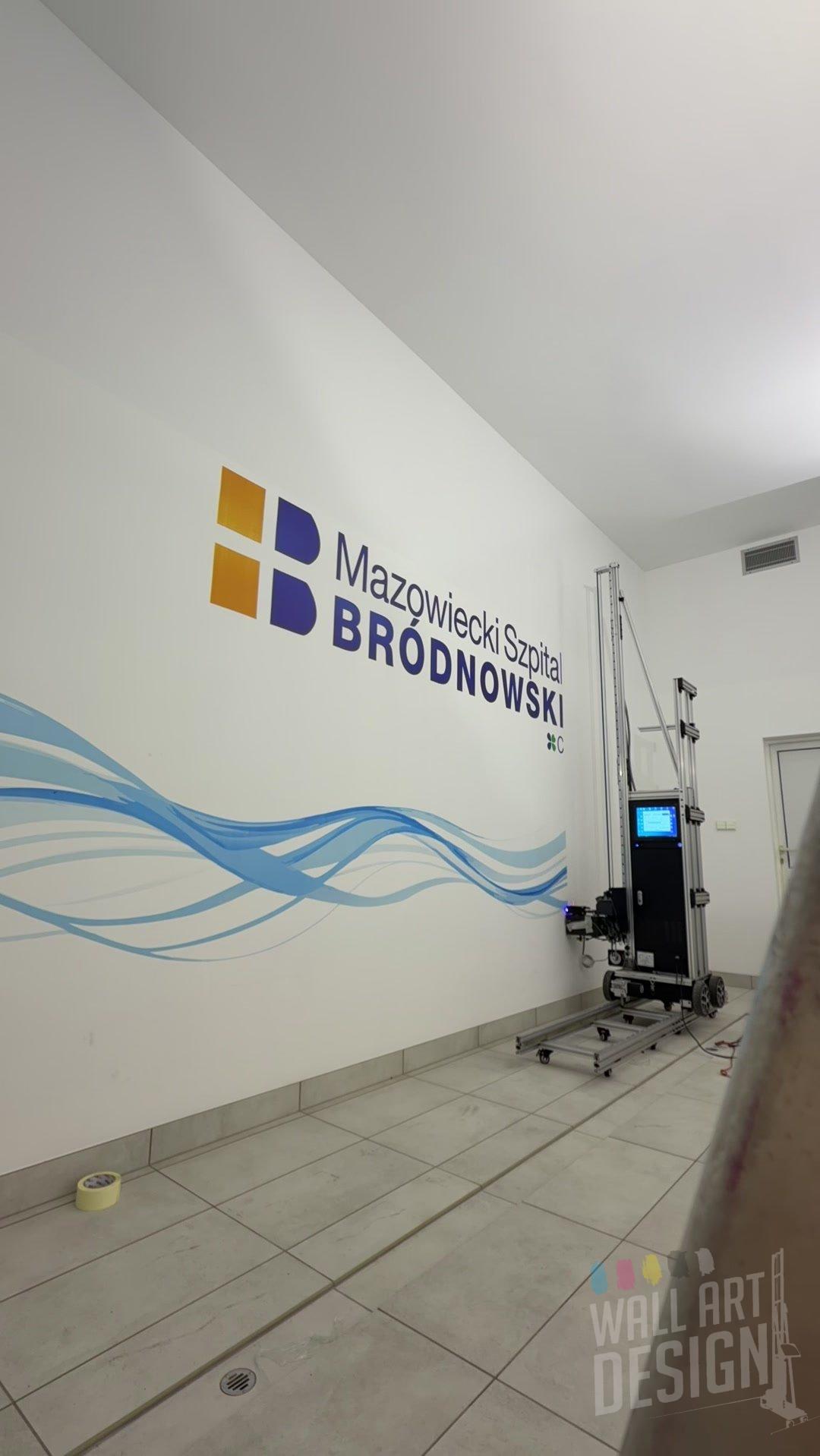 Gotowa ściana z logo Szpitala Bródnowskiego i falami – druk ścienny UV na basenie rehabilitacyjnym