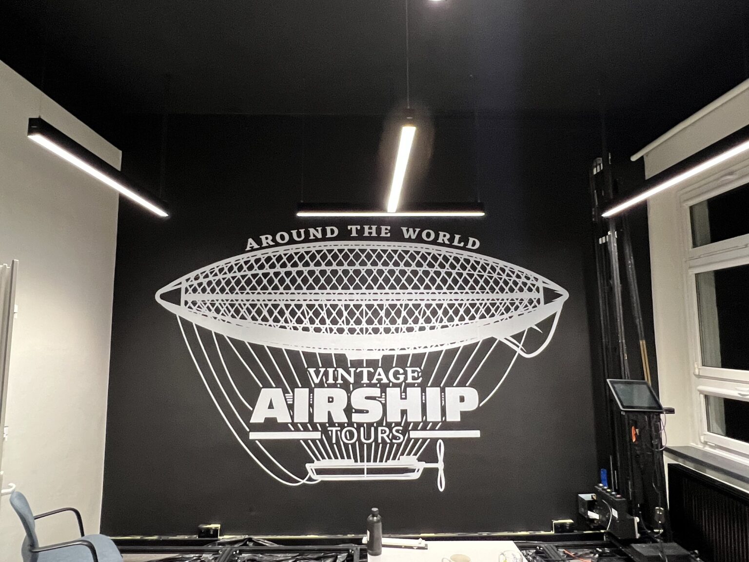 Druk ścienny UV – biały sterowiec „Vintage Airship Tours” na czarnej ścianie