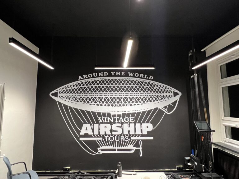 Druk ścienny UV – biały sterowiec „Vintage Airship Tours” na czarnej ścianie